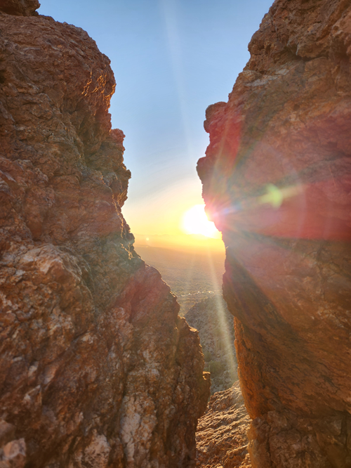 Picture of sun rising seen through two rocks in Arizona
